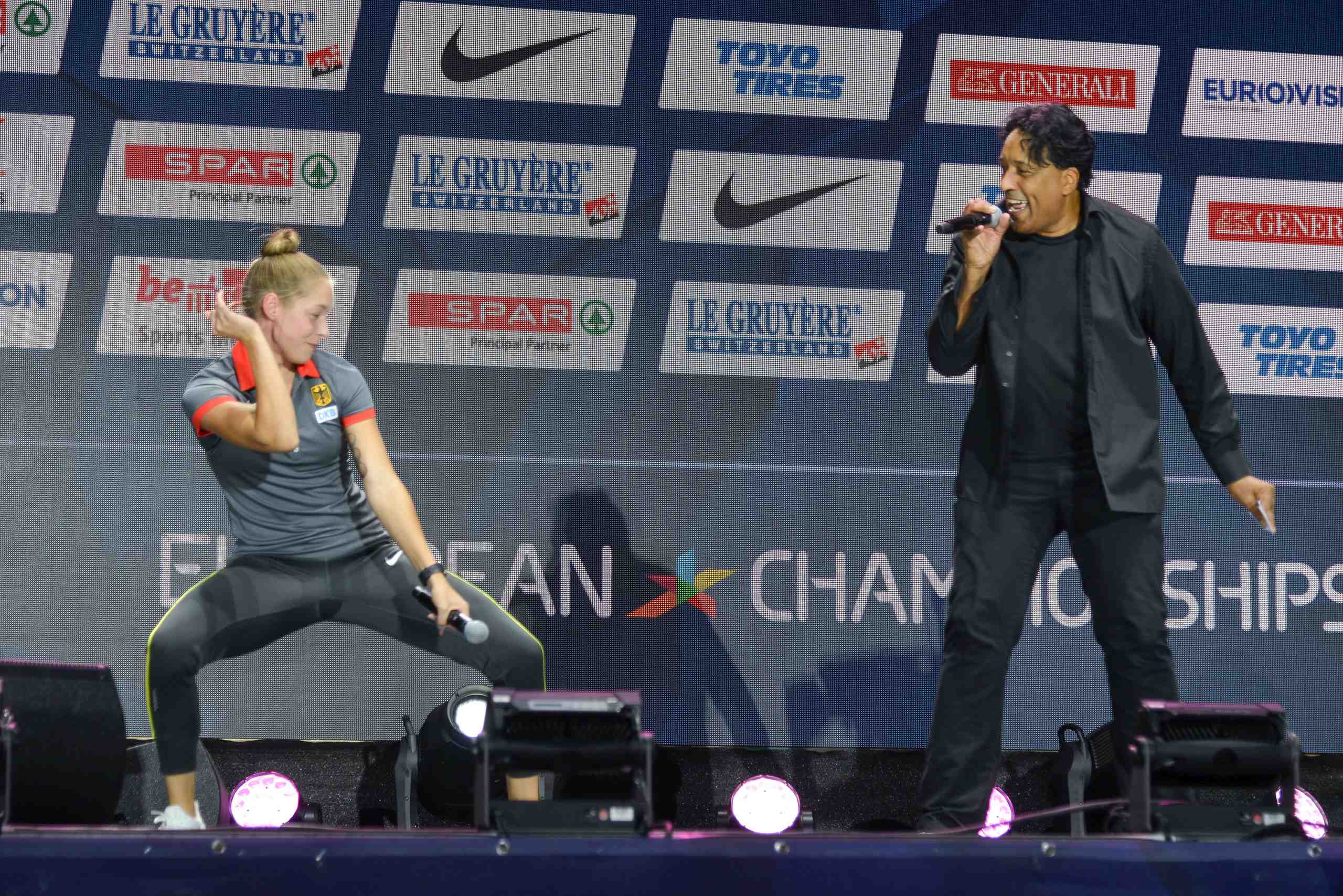 Gina Lückenkemper dances while host Cherno Jobatey raps at the medal ceremony of the European Athletics Champioships 2018